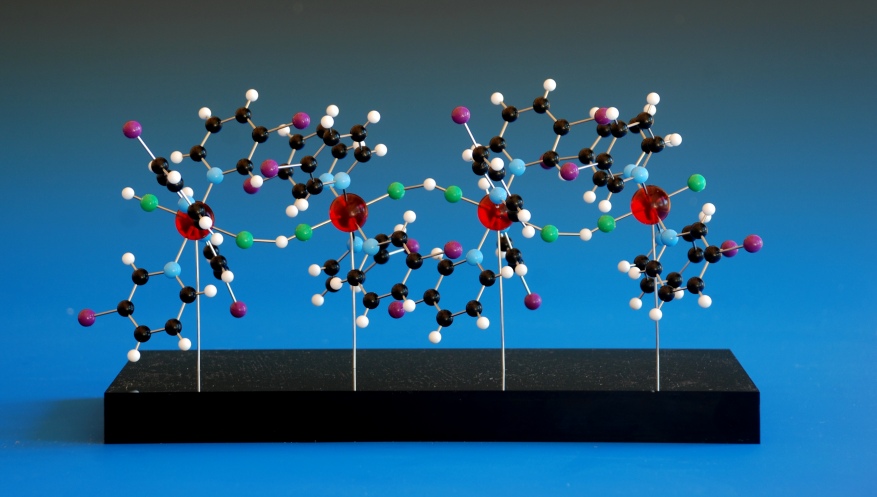 A ball and stick model of a polymeric coordination compound on a black acrylic base
